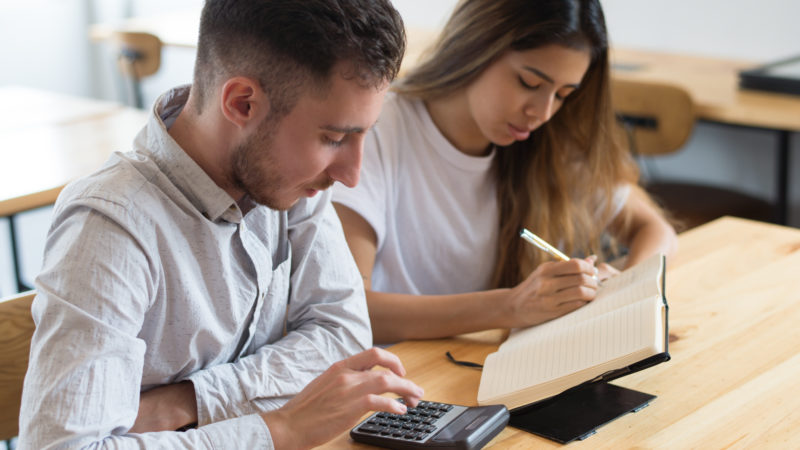 Focused students using calculator and studying together